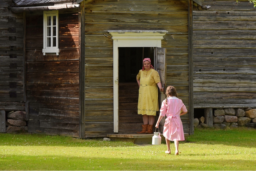 Emäntä odottaa kuistilla, kun tytär palaa maitolaiturilta